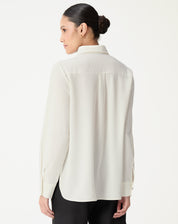 Vista traseira da camisa alongada off-white mostrando a pala com prega central e barra arredondada