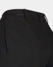 Detalhe lateral e traseiro do shorts preto mostrando bolso embutido e caimento estruturado no quadril