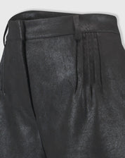 Detalhe em close do tecido suedine com acabamento metalizado do shorts preto, evidenciando textura e costuras