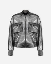 Imagem em corpo inteiro da modelo usando jaqueta bomber prata com shorts prateados e sandálias, look curto e descolado