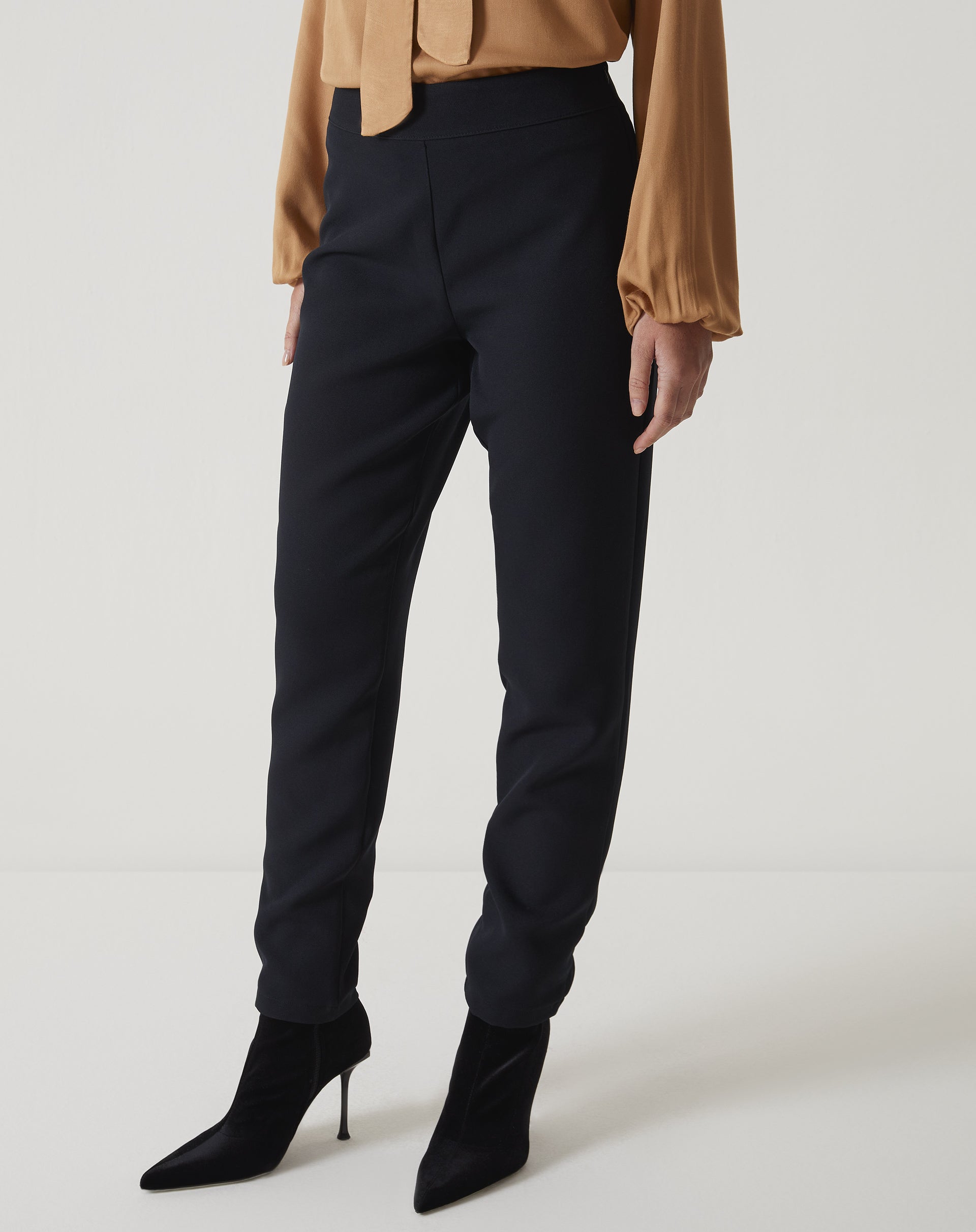 Vista lateral da calça slim preta de alfaiataria com bainha aplicada.