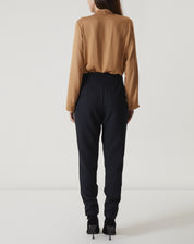 Detalhe do tecido e acabamento da calça slim preta de alfaiataria.