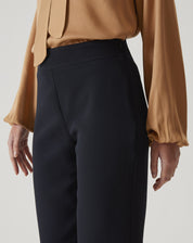 Detalhe do cós alto da calça slim preta de alfaiataria.