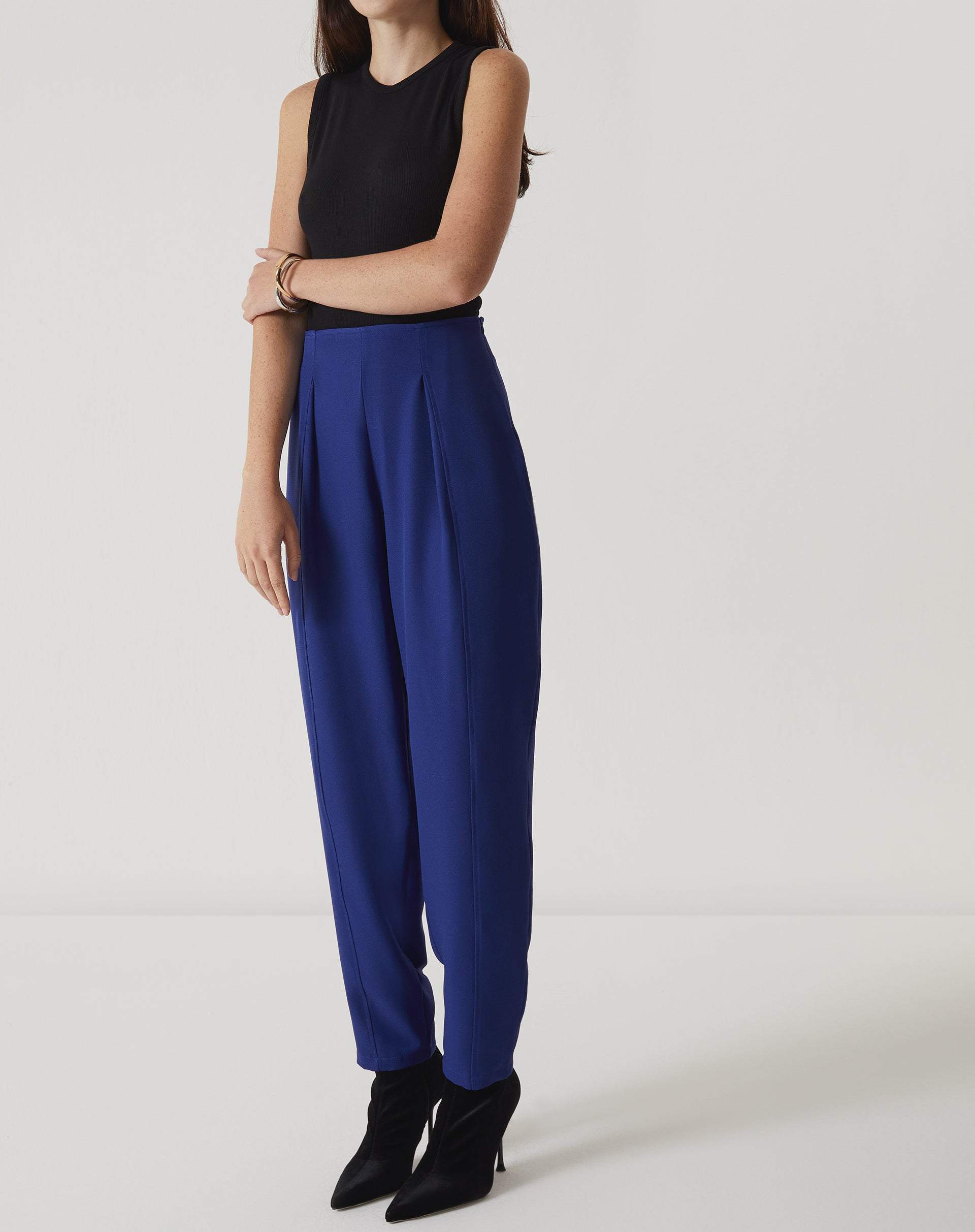 Modelo vestindo a regata curta de malha preta com calça azul, mostrando um look completo.