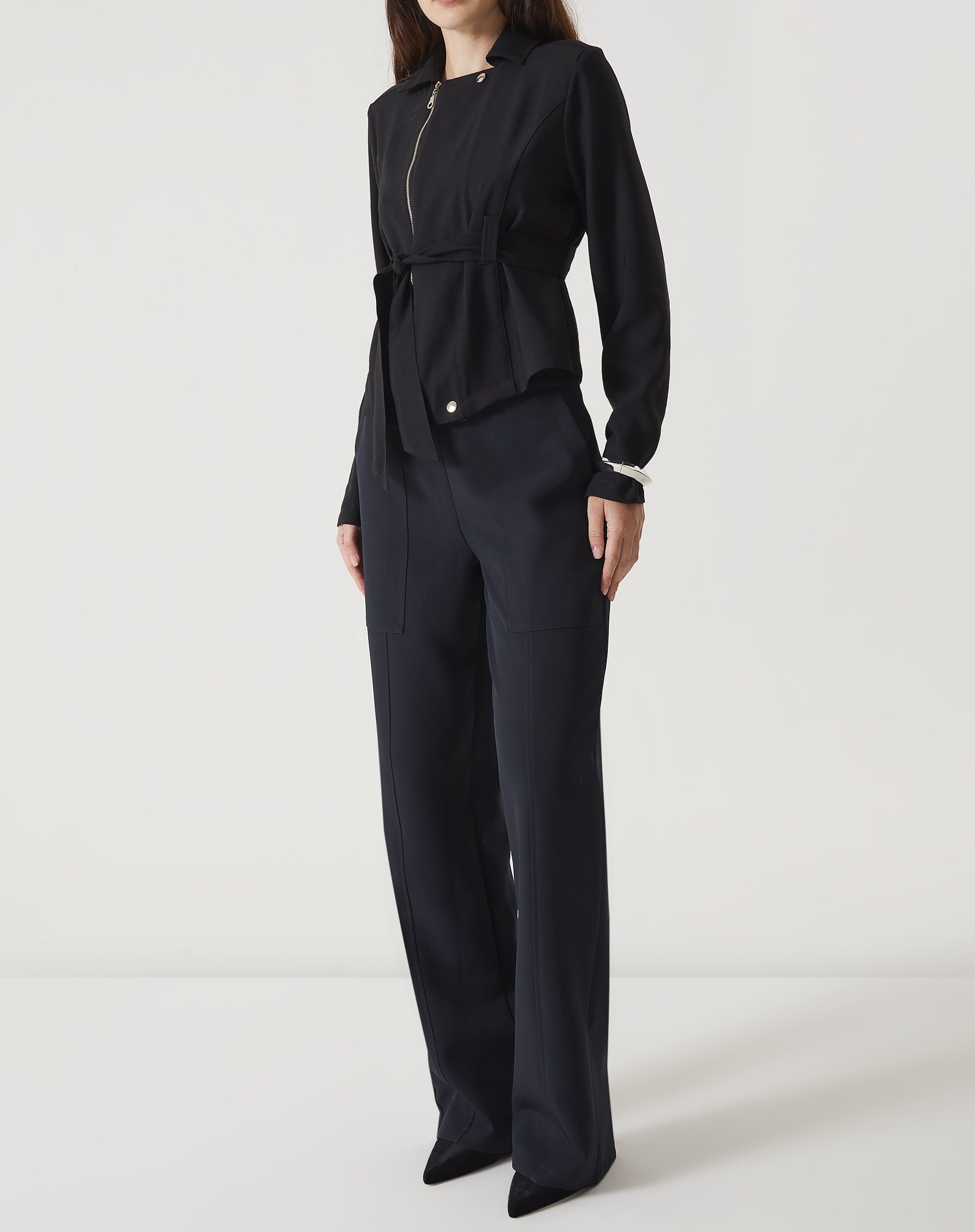 Modelo vestindo calça reta de alfaiataria preta com blazer preto, vista frontal.