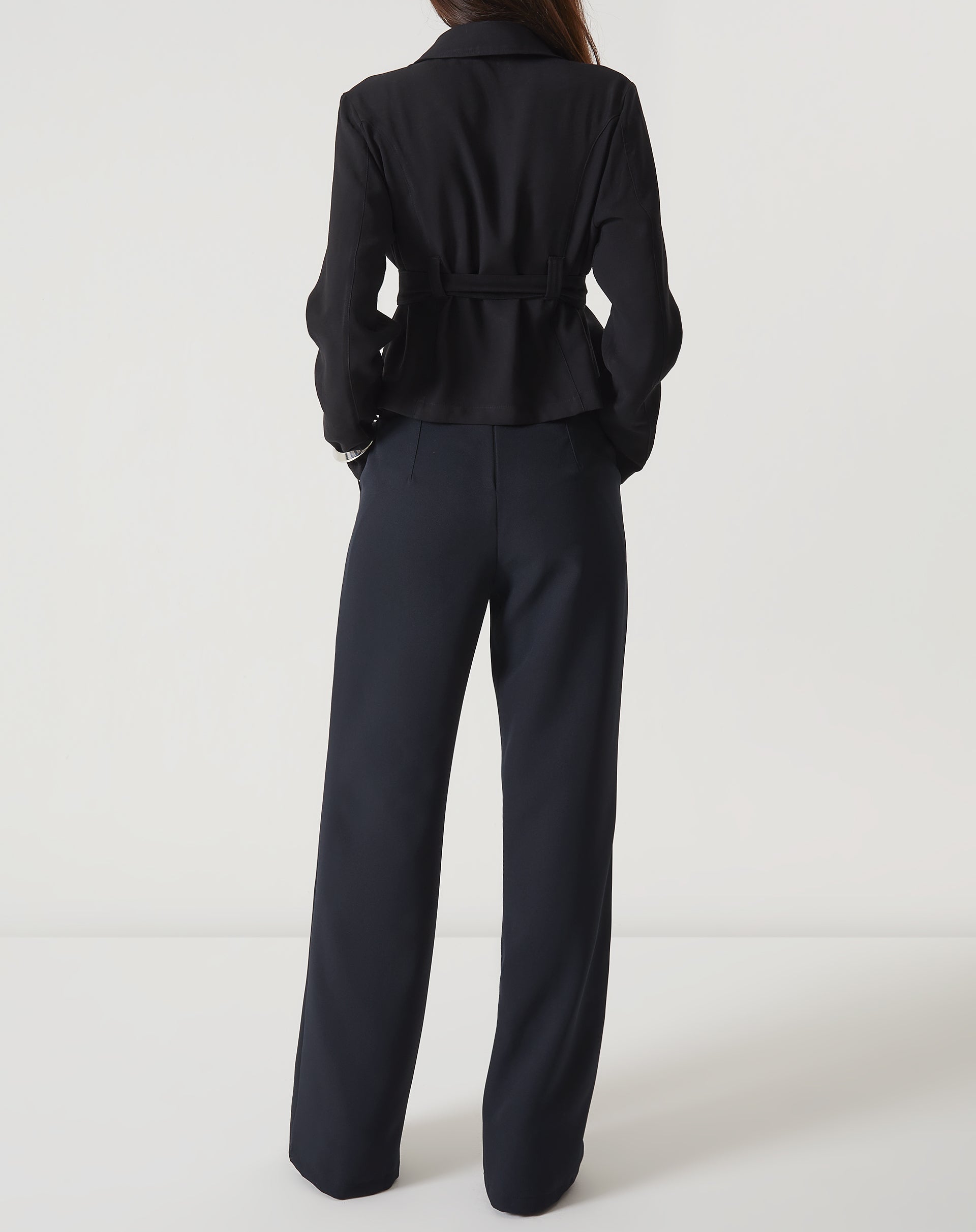 Vista traseira da calça reta de alfaiataria preta com blazer preto.