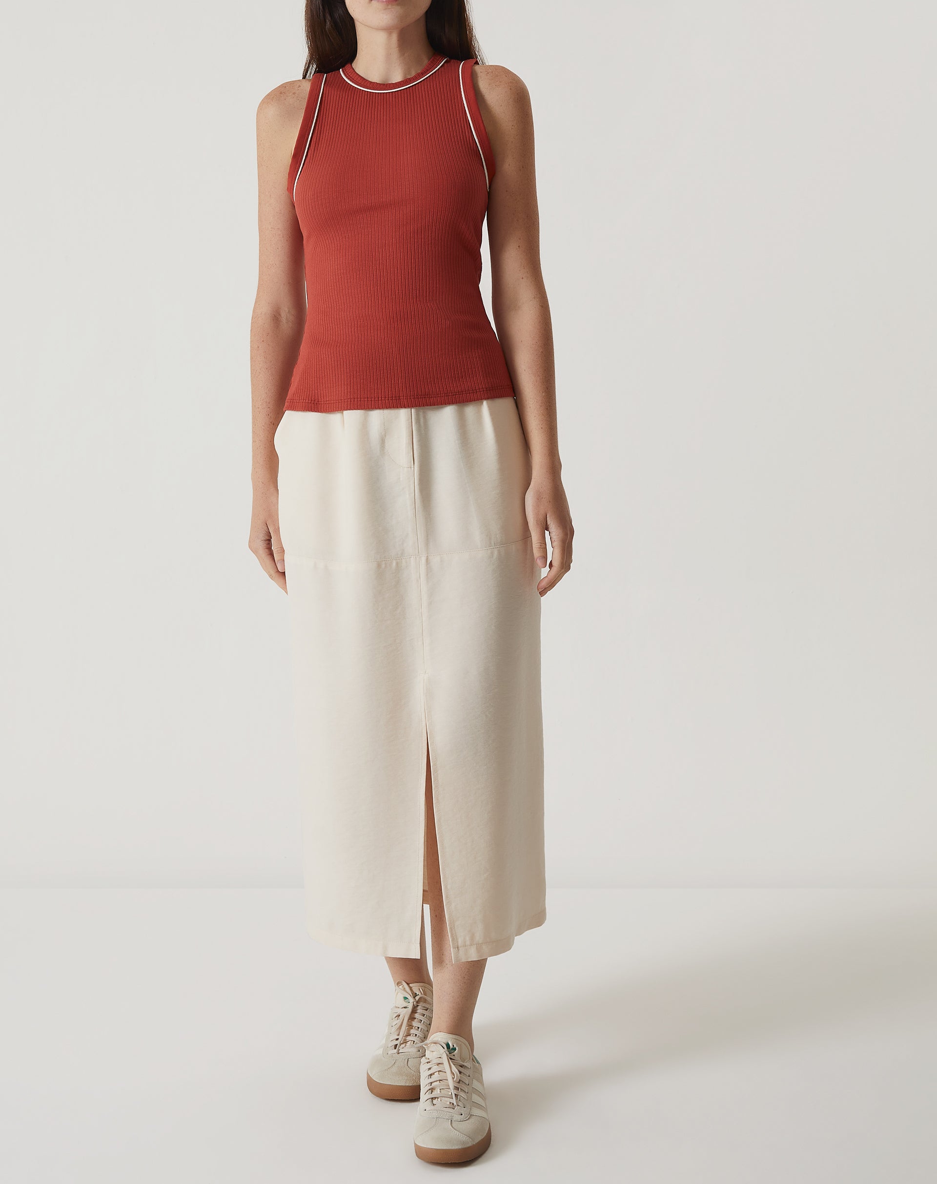 Regata Slim de Malha em laranja, modelo vestindo com saia branca.