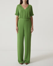 Imagem de um macacão verde com manga curta e decote em V, visto de frente.