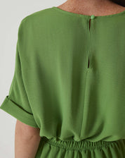 Detalhe da cintura ajustada do macacão verde com elástico.