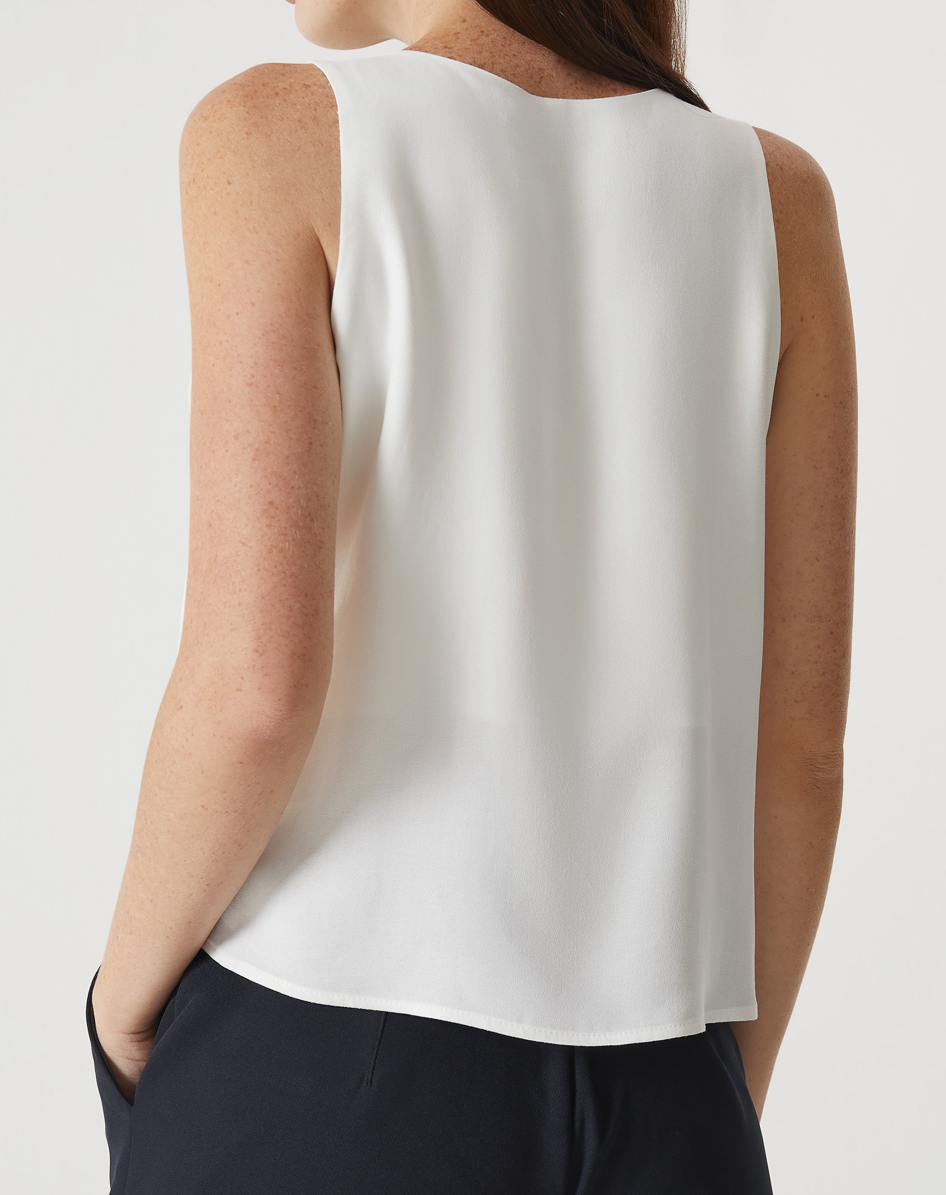 Regata off-white com babados, vista traseira mostrando a barra arredondada.