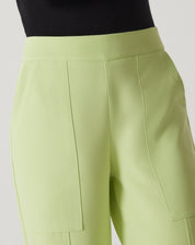 Detalhe do cós e bolsos frontais da calça reta de alfaiataria verde claro.