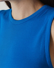 Vista lateral da regata curta de malha azul, destacando o caimento ajustado.