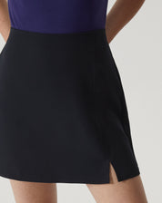 Detalhe lateral da saia curta de alfaiataria preta com acabamento liso.