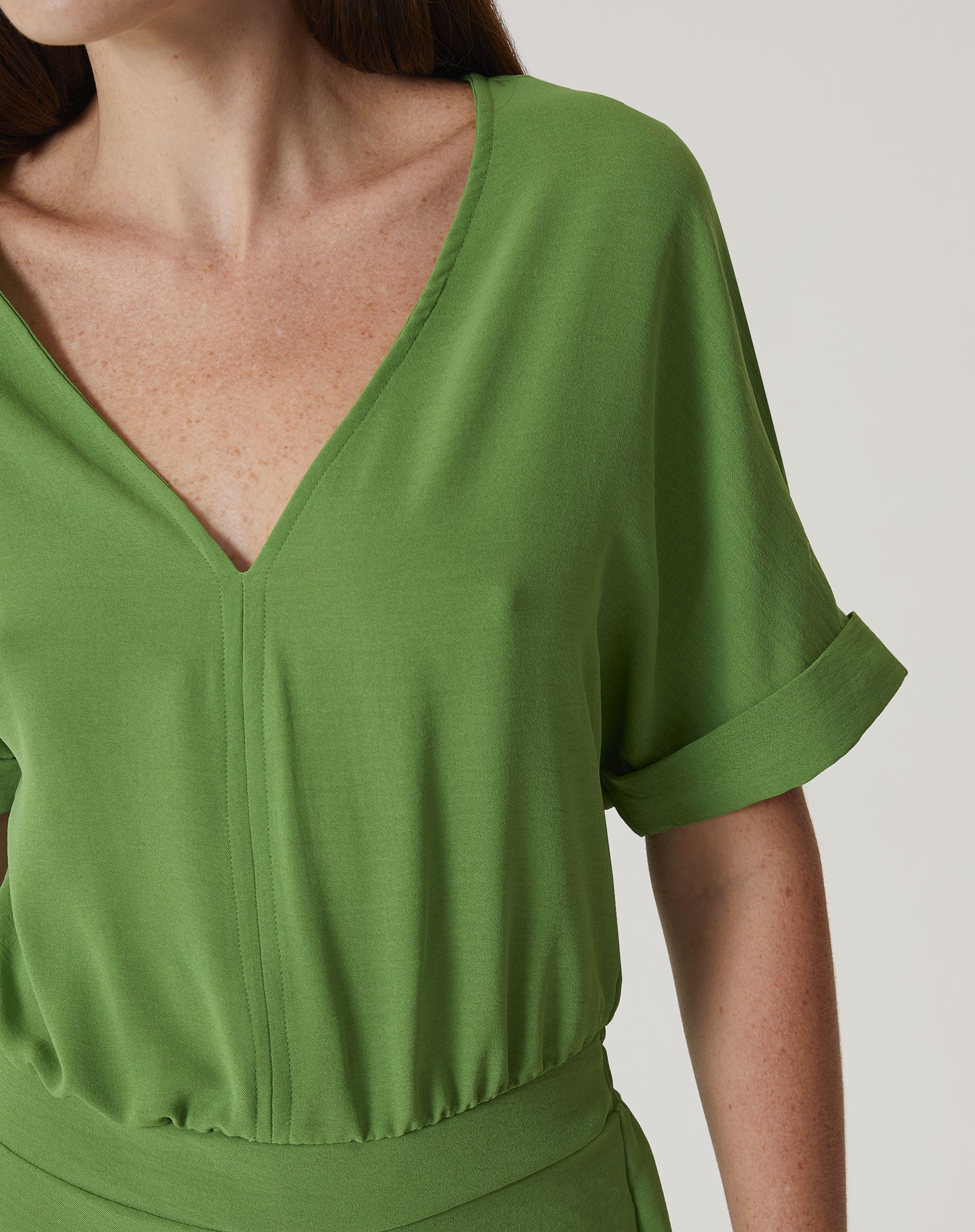 Close-up do tecido verde do macacão mostrando sua textura.