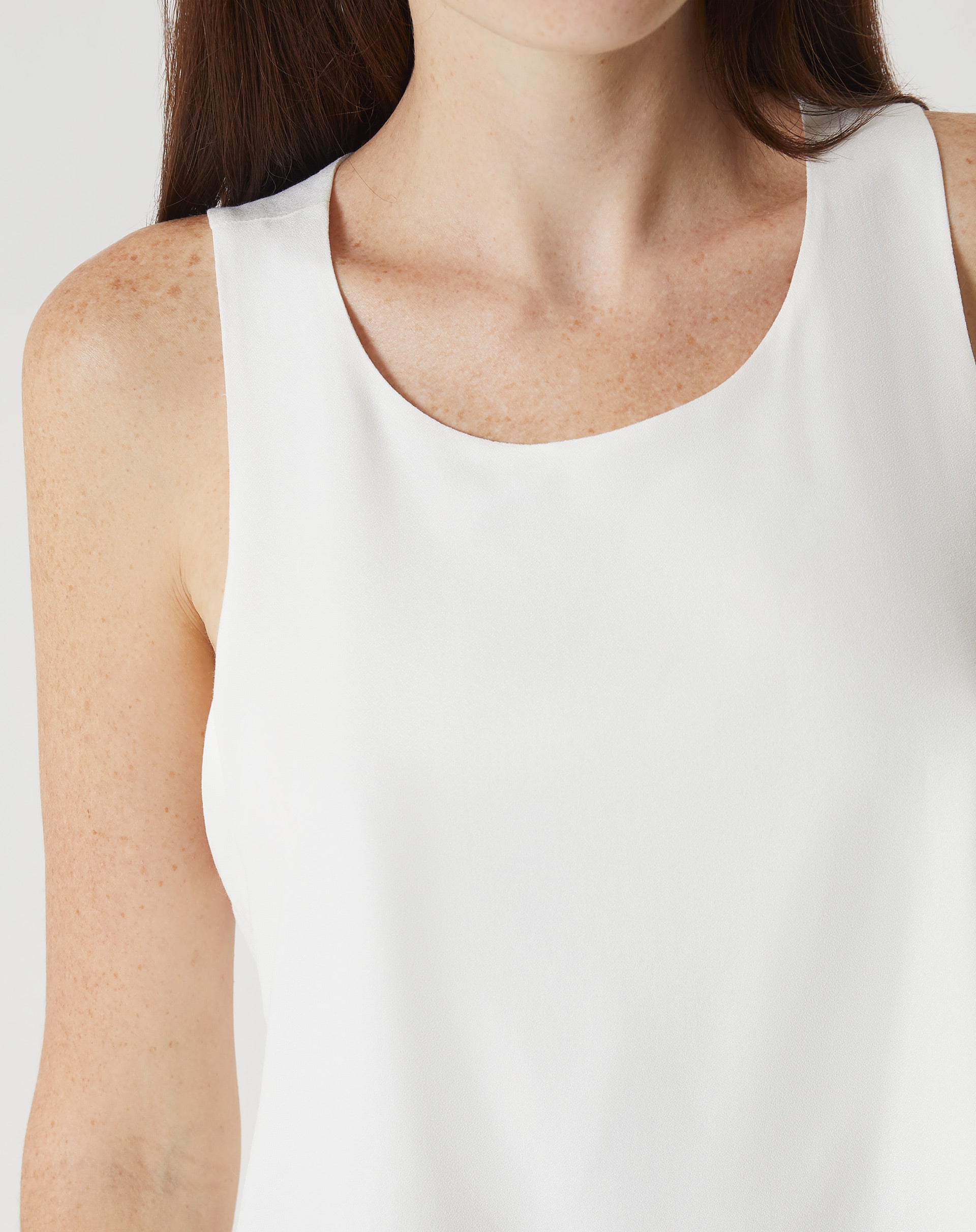 Detalhe do decote redondo da regata off-white com babados.