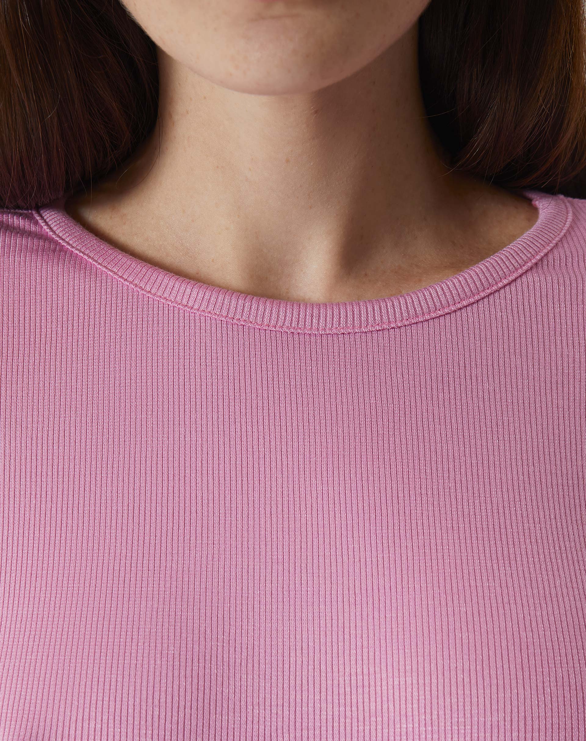 Detalhe da gola redonda da blusa manga longa rosa.