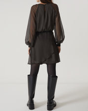 Vista traseira do vestido curto verde com mangas longas bufantes, mostrando o fechamento.