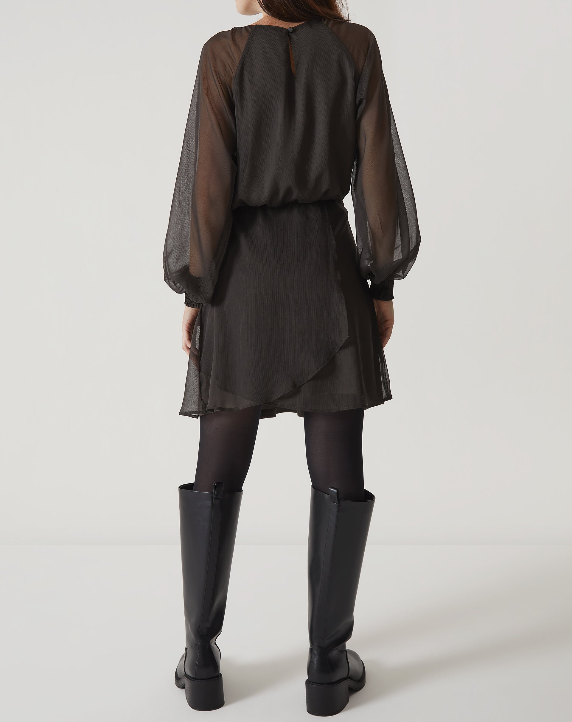 Vista traseira do vestido curto verde com mangas longas bufantes, mostrando o fechamento.