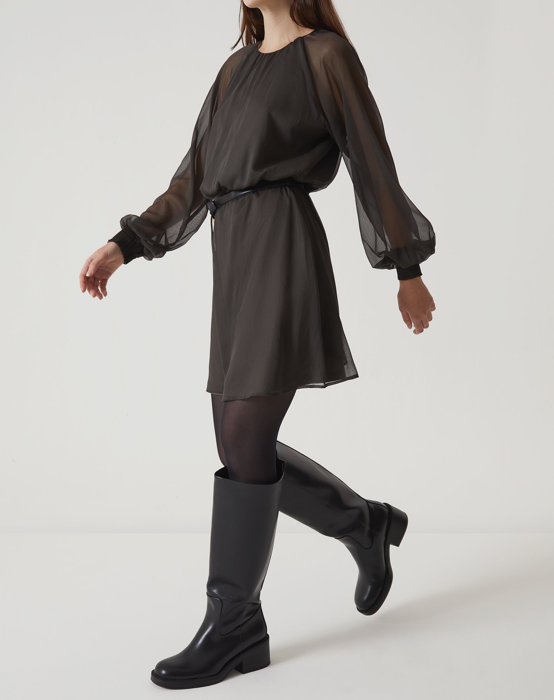 Vista lateral do vestido curto verde com mangas longas bufantes, destacando o caimento.