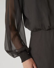 Detalhe da manga longa bufante do vestido curto verde, com punho ajustado.