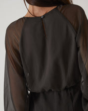 Close-up do fechamento traseiro do vestido curto verde, com botão.