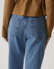 Detalhe dos bolsos traseiros da calça jeans azul médio.