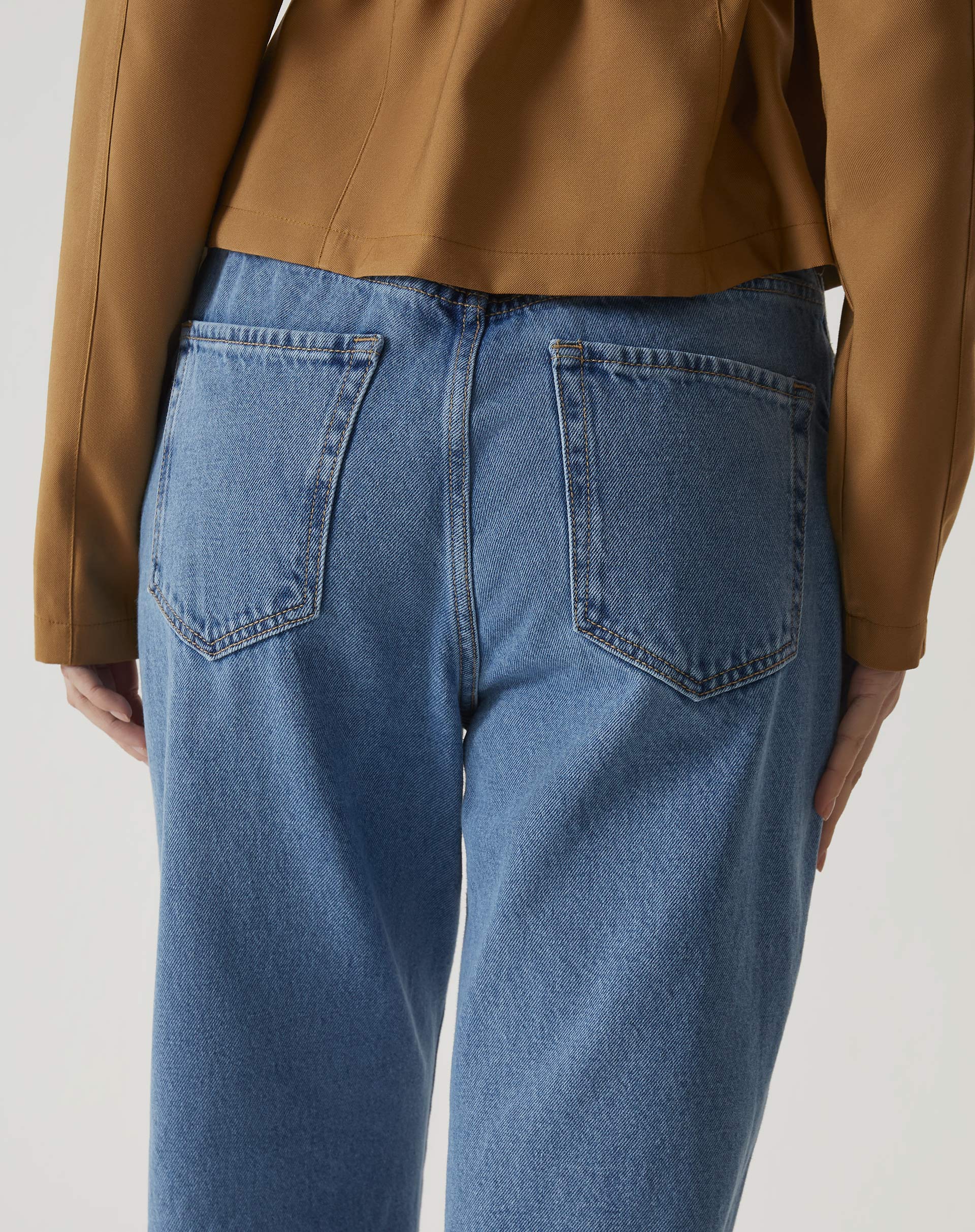 Detalhe dos bolsos traseiros da calça jeans azul médio.