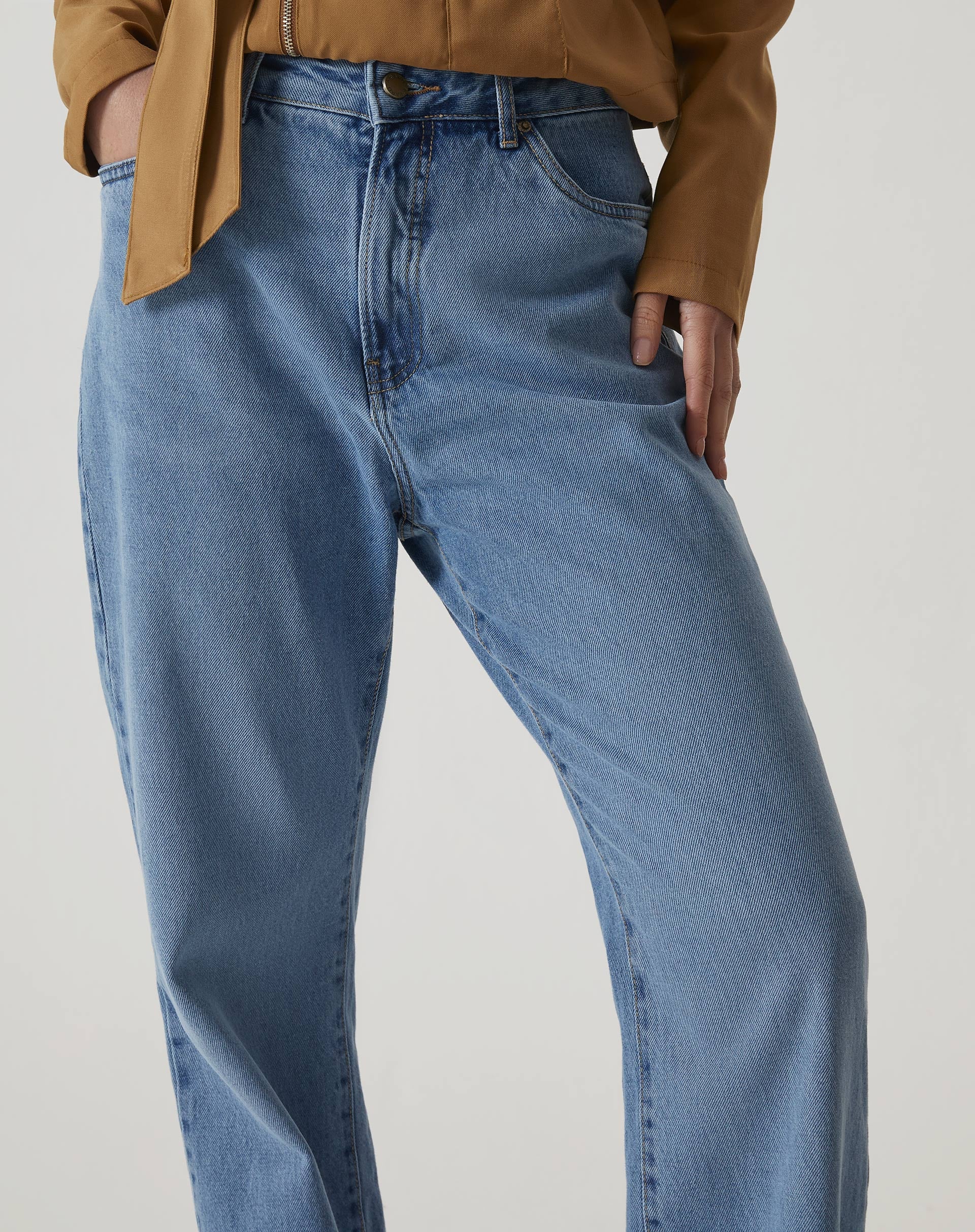 Detalhe da cintura alta da calça jeans azul médio.