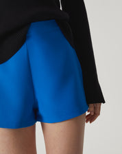 Vista lateral do shorts azul destacando o caimento e tecido.