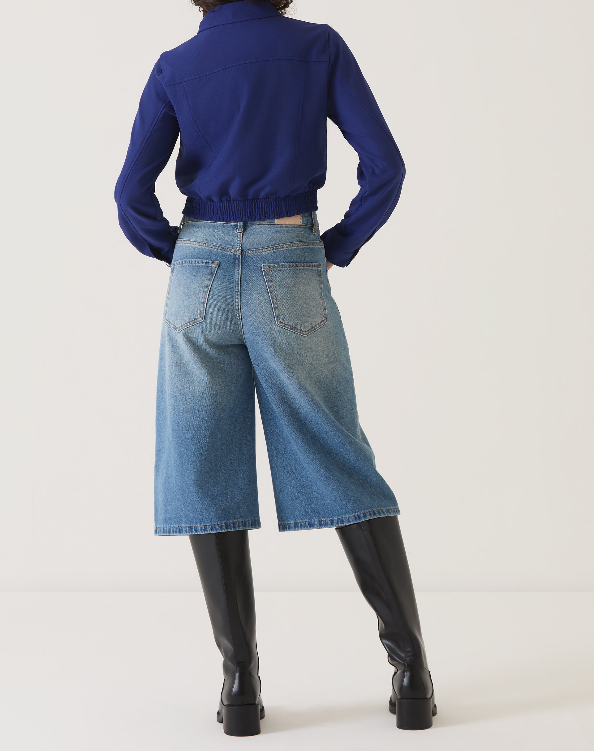 Detalhe lateral da jaqueta azul escuro destacando o tecido de alta qualidade.