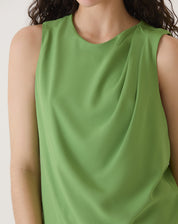 Detalhe do tecido fluido da blusa sem mangas de crepe verde, evidenciando o acabamento.