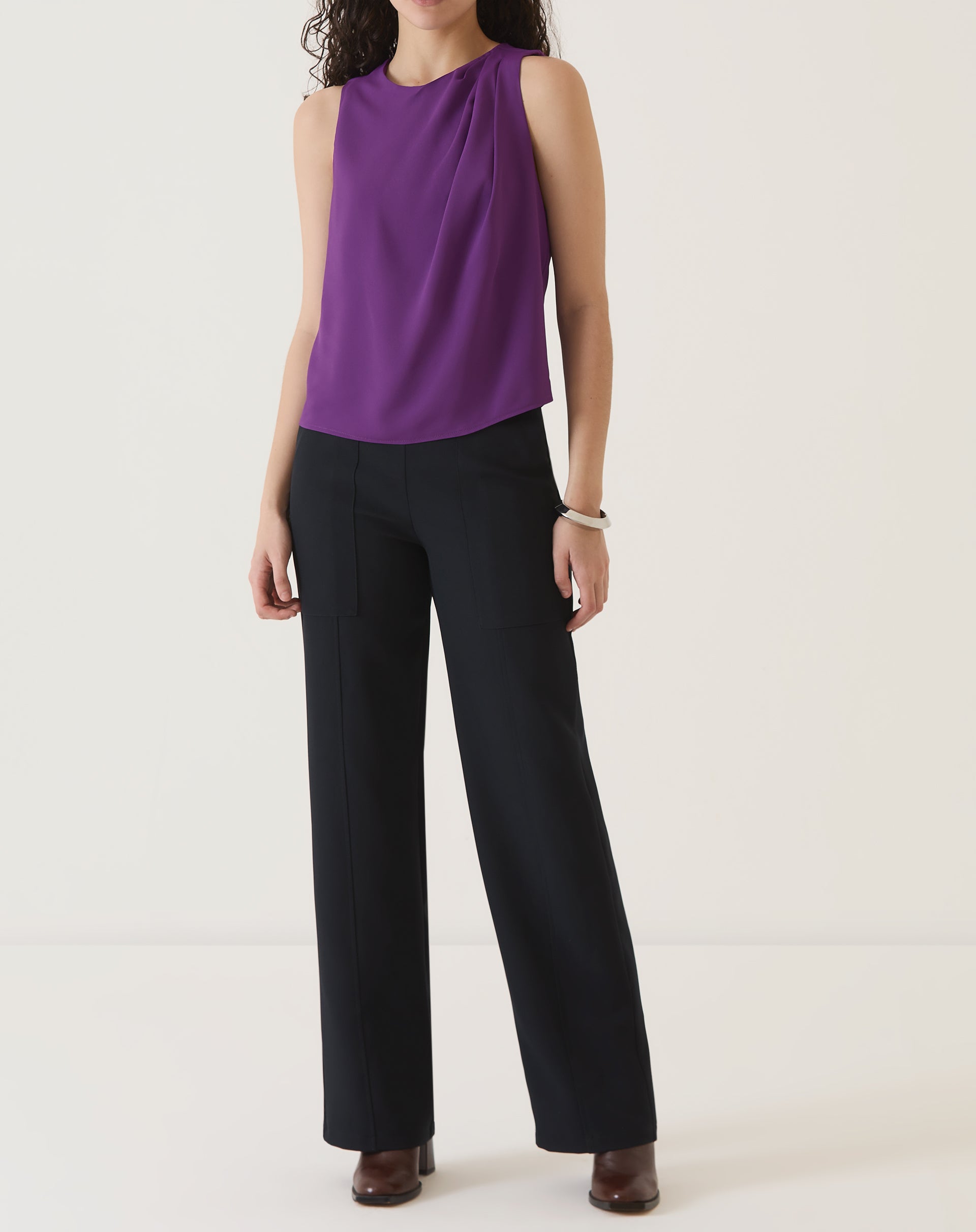 Vista completa da blusa sem mangas de crepe roxo combinada com calça preta.