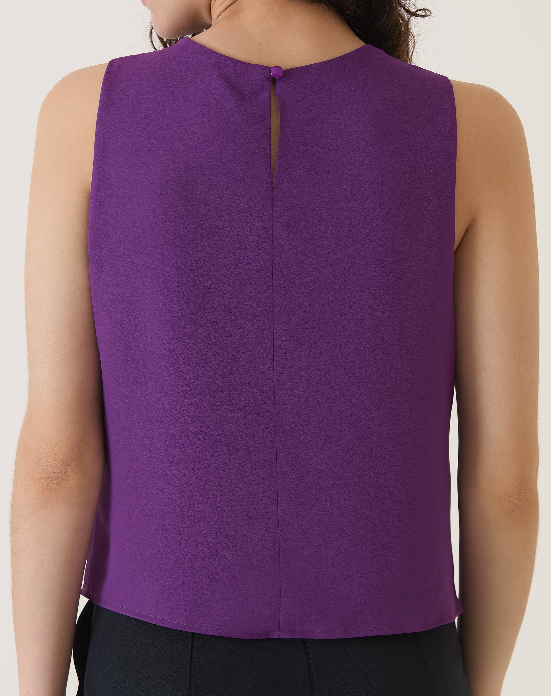 Vista traseira da blusa sem mangas de crepe roxo, mostrando o fechamento discreto.