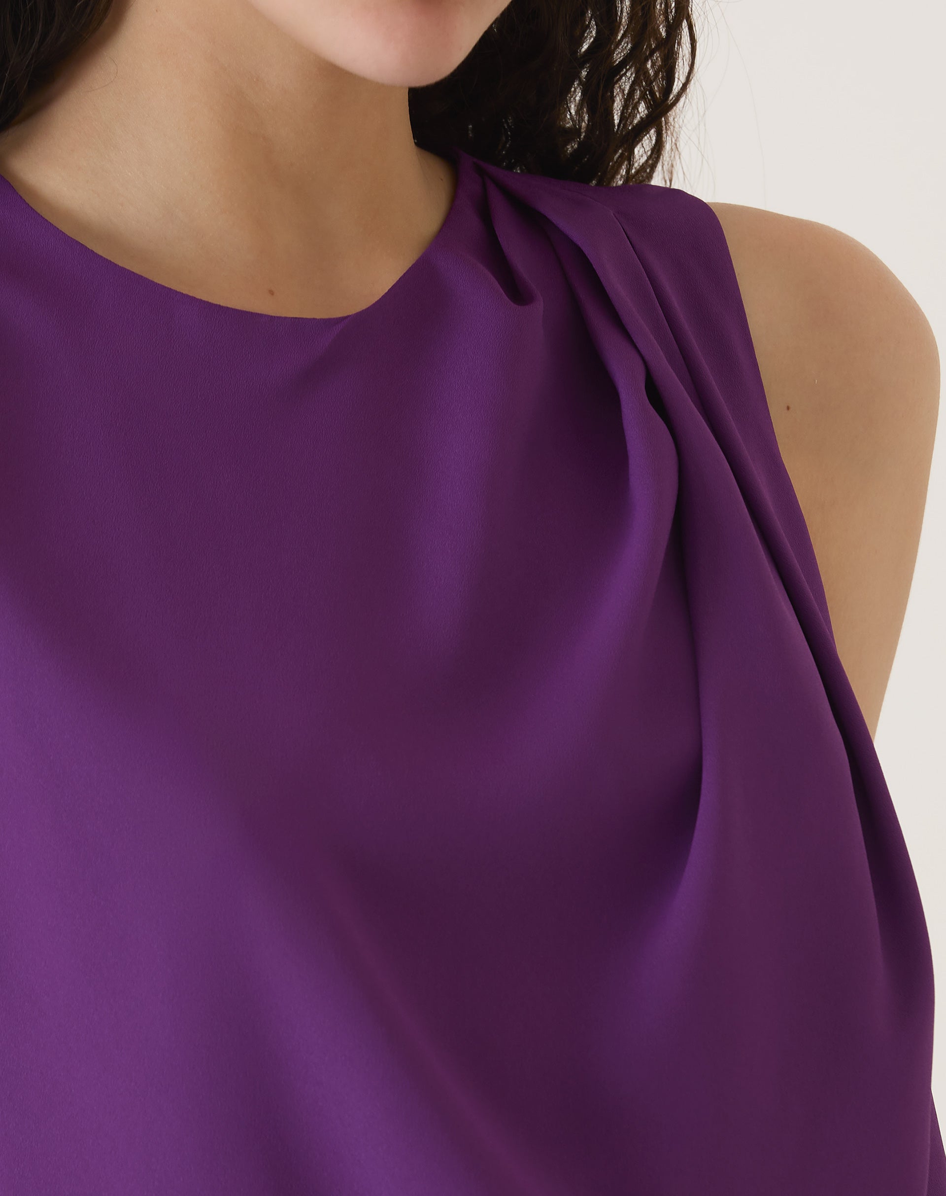 Close-up do detalhe do tecido fluido e do design minimalista da blusa sem mangas de crepe roxo.