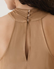 Detalhe do fechamento traseiro da blusa bege, com botões elegantes.