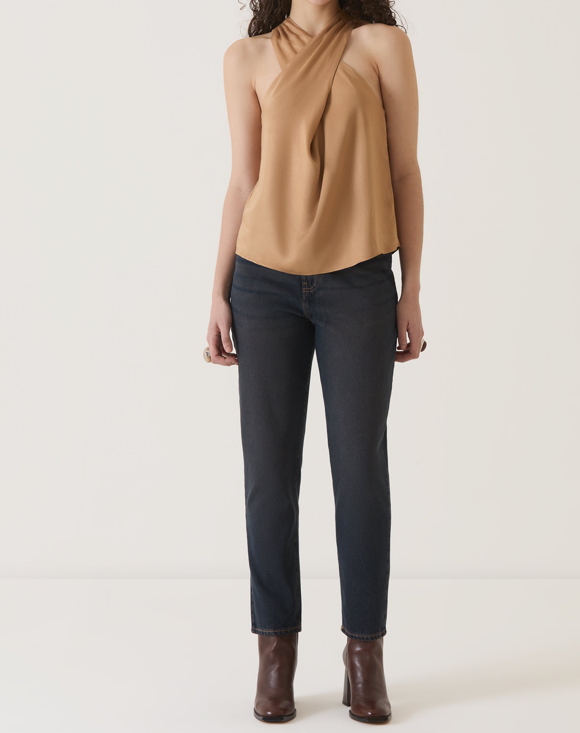 Vista completa da blusa bege com decote transpassado, combinada com calça jeans.