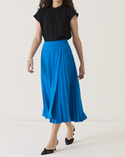 Modelo vestindo saia azul com pregas e blusa preta, vista frontal.