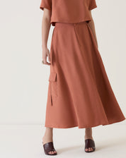 Vista lateral da saia midi bege, destacando o comprimento e o caimento.