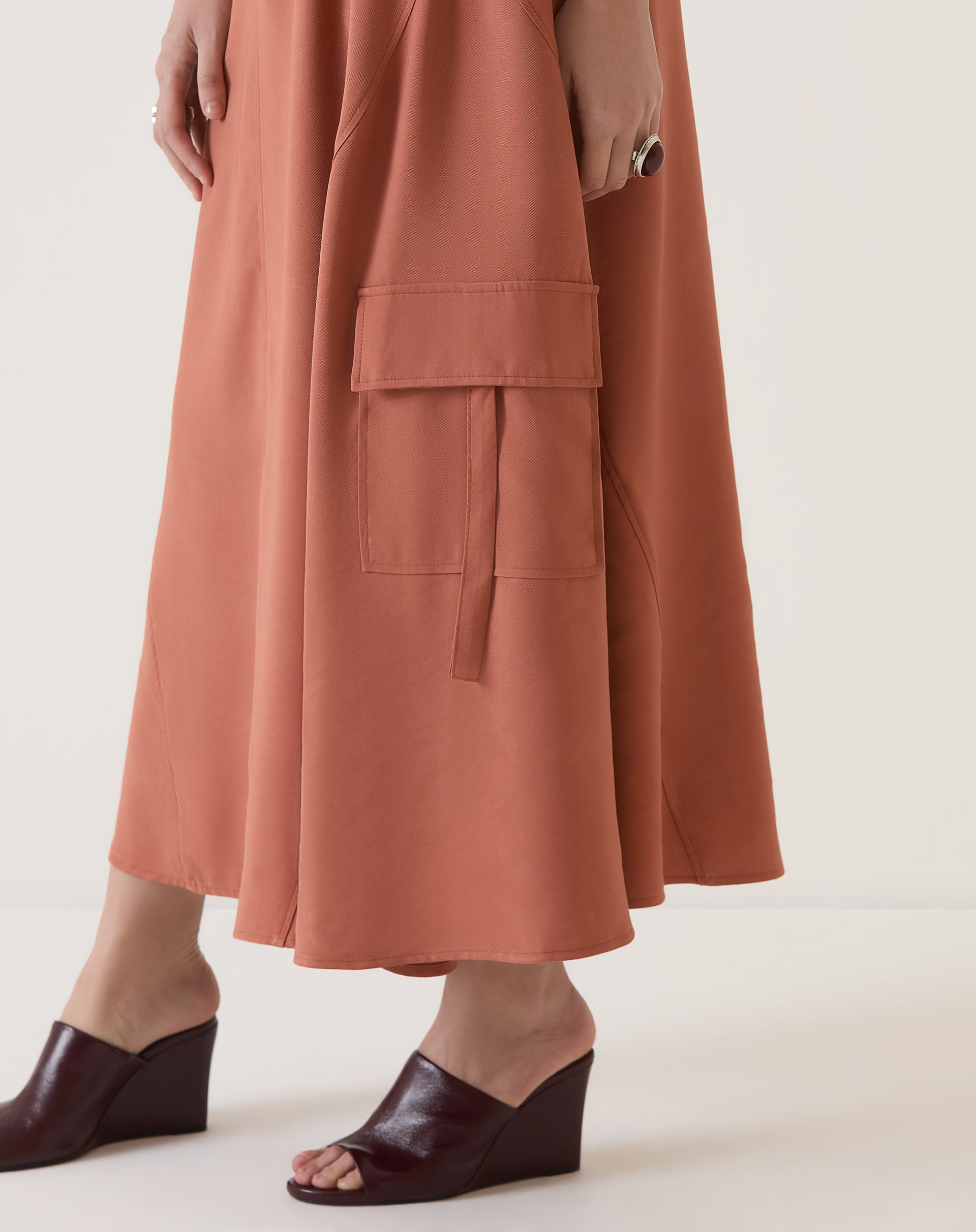 Detalhe dos bolsos cargo na saia bege, mostrando funcionalidade.