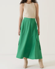 Modelo vestindo saia verde com bolsos cargo, vista frontal completa.