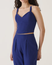 Blusa azul com alças de alfaiataria, vista frontal mostrando o decote em V e o comprimento cropped.