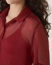 Imagem de uma camisa manga curta vinho com design moderno e tecido transparente.