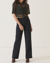 Modelo vestindo camisa manga curta preta com calça preta.