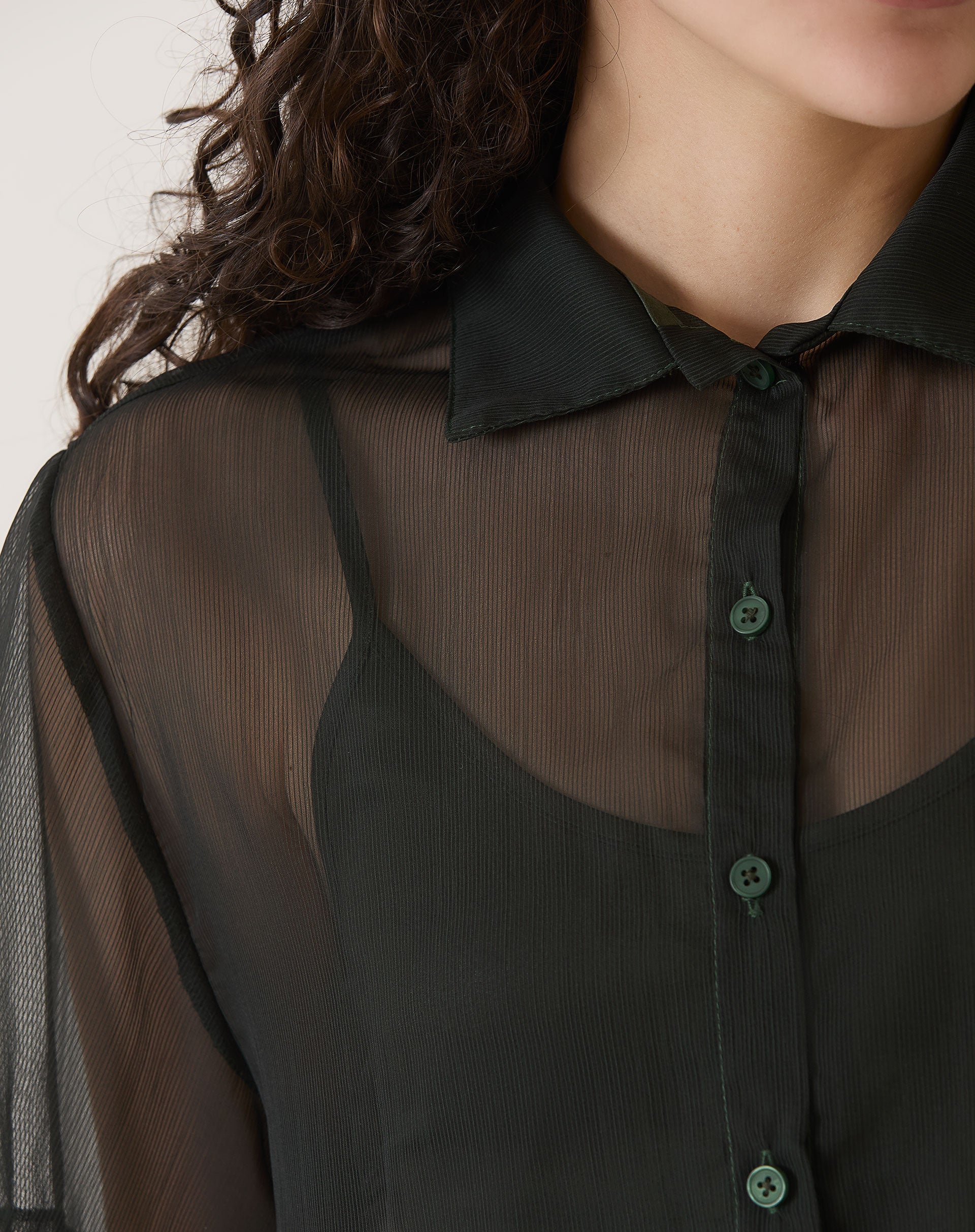 Detalhe do colarinho e fechamento frontal com botões da camisa preta.