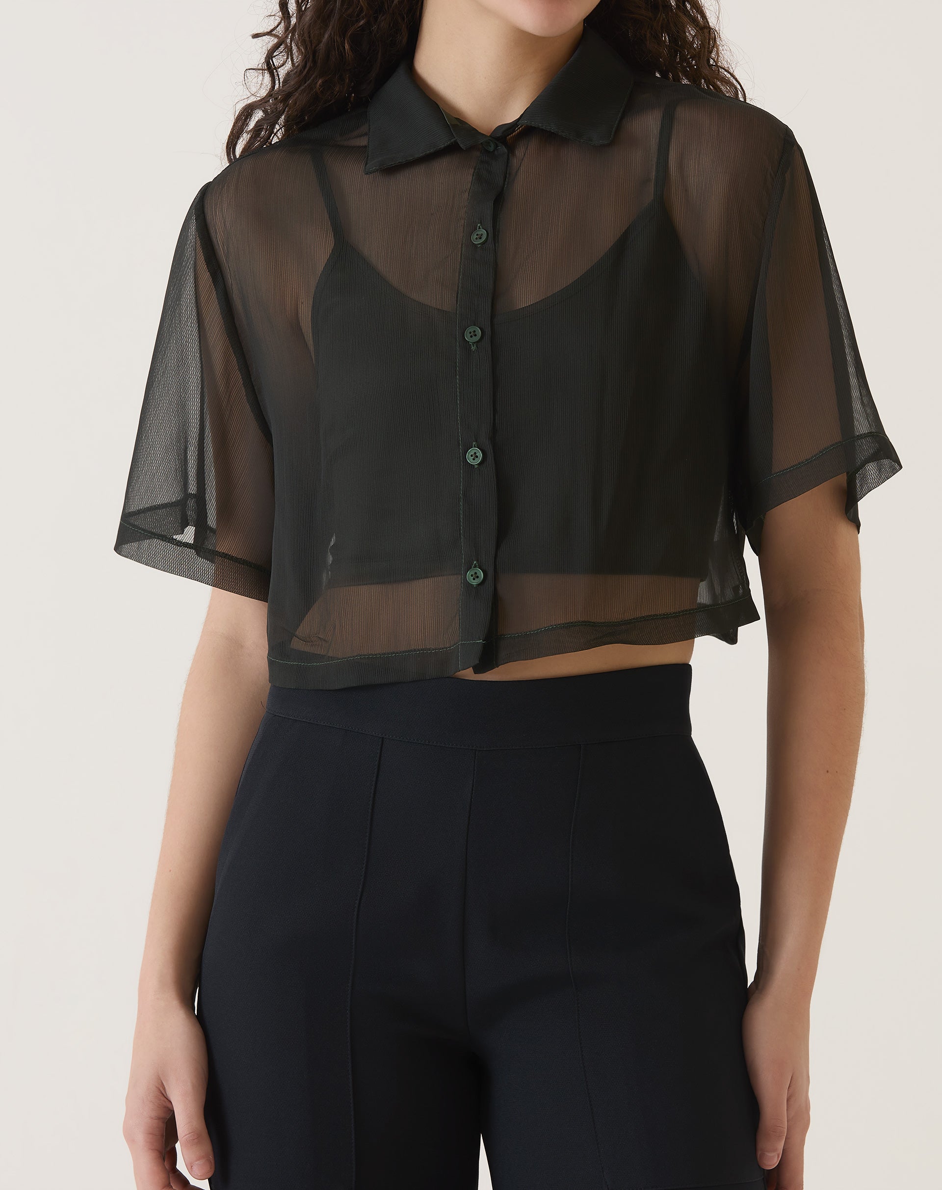 Modelo vestindo camisa manga curta preta com calça preta, vista frontal.