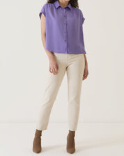 Modelo vestindo camisa de cetim roxa com calça clara e botas.