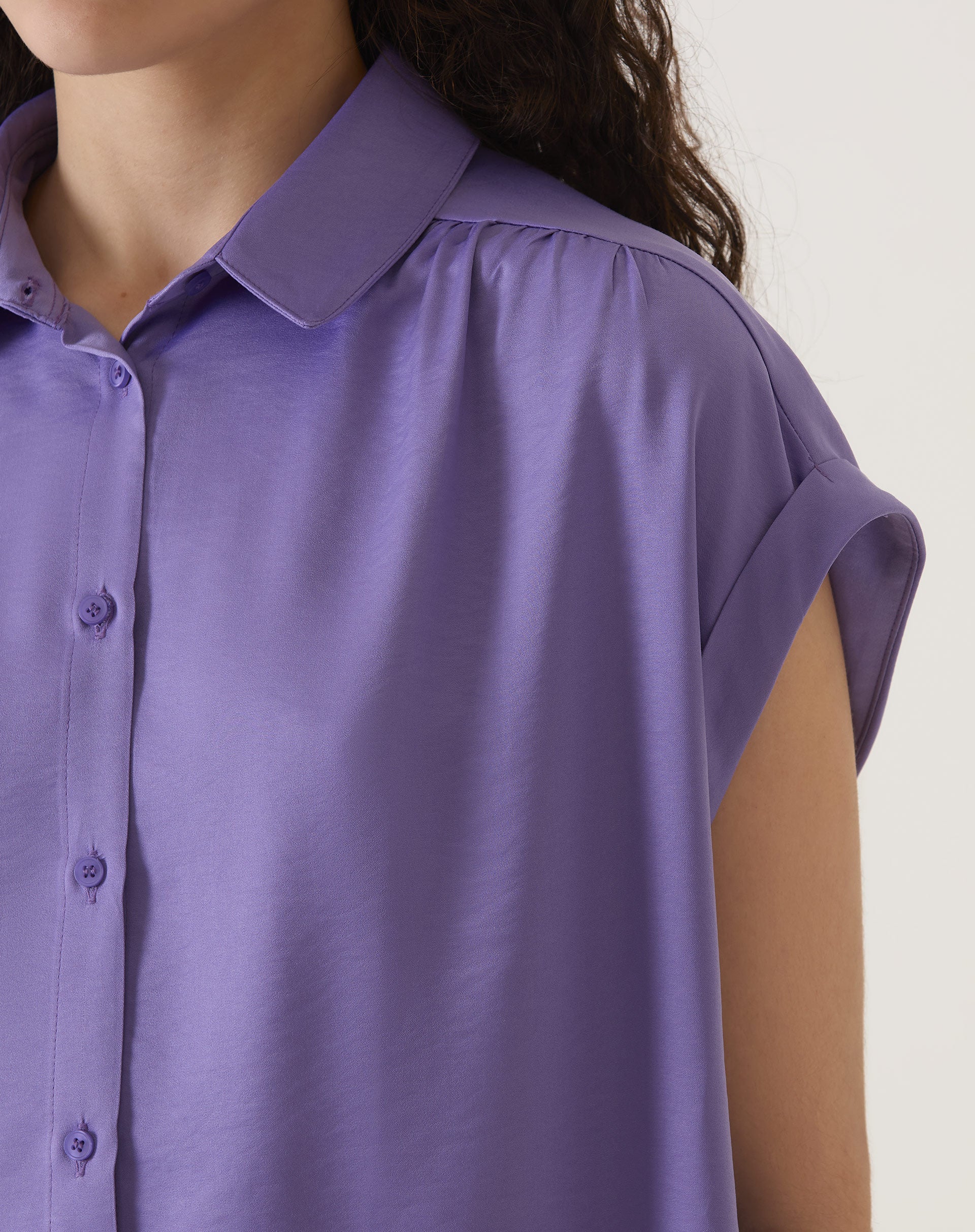 Detalhe do colarinho e fechamento com botões da camisa de cetim roxa.