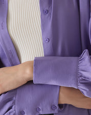 Detalhe do tecido e botões da camisa de cetim roxo.