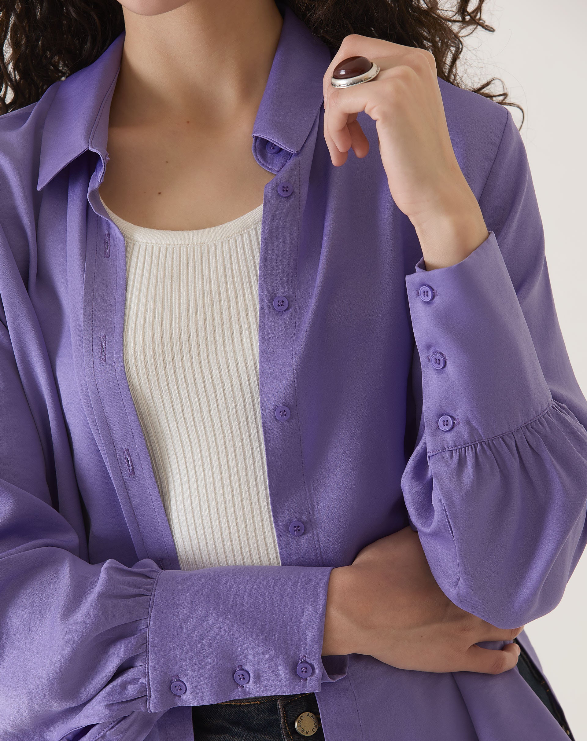 Detalhe do punho da camisa de cetim roxo com manga longa.