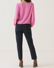 Vista traseira da blusa rosa, mostrando o corte reto e o comprimento até a cintura.